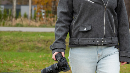 Photographer Holding Camera in a Park During Autumn, Showcasing Nature's Colors and Textures