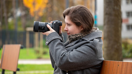 Woman Captures Autumn Beauty With a Camera in an Urban Park Setting During a Cool Afternoon