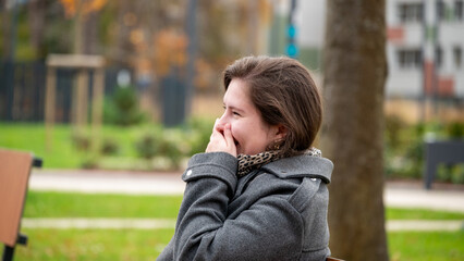 Woman Laughing in a Park During Autumn, Enjoying a Cheerful Moment With Friends and Nature