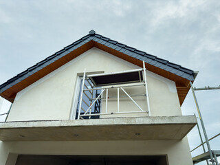 Building renovation project showcasing scaffolding under a cloudy sky outside a newly constructed home in a suburban area
