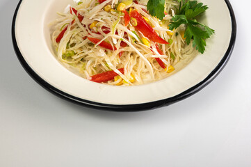 Fresh, colorful coleslaw or spring salad with cabbage, red pepper, and corn in a vintage enamel bowl on a white background with copy space