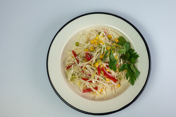 Fresh, colorful coleslaw or spring salad with cabbage, red pepper, and corn in a vintage enamel bowl on a white background with copy space