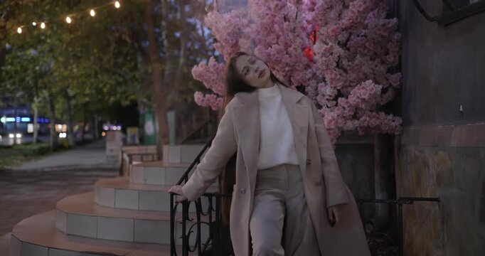 Woman smokes an electronic cigarette at the night city near blossom cherry