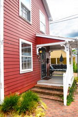 Exterior door of red siding home with brick steps at entrance and patio with seating areas