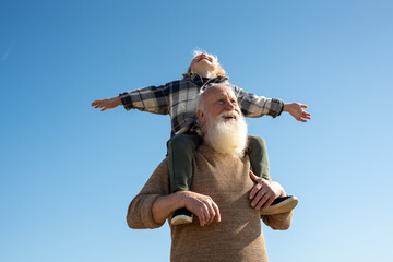 Grandfather carrying his grandson on his shoulders, walking along the beach