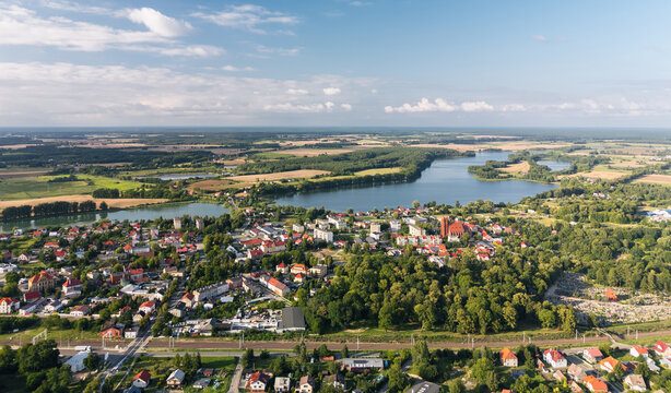 Aerial panorama of Dobiegniew, Lubuskie, Poland. Skyline view with a church, colorful residential buildings, lush greenery, and Wielgie Lake on a summer day
