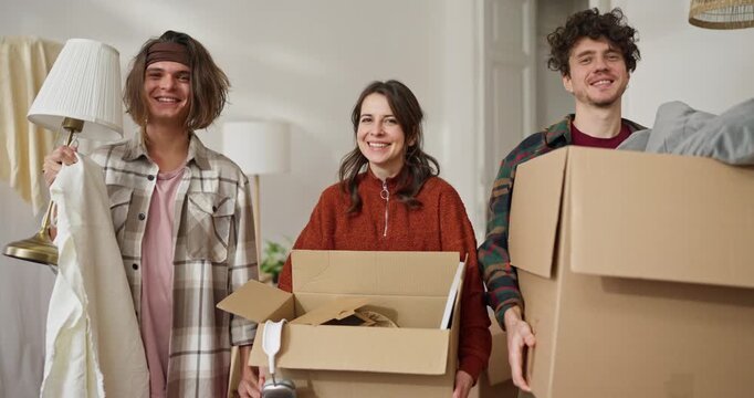 Portrait of a trio of friends posing and smiling while holding cardboard boxes of furniture during their move. Portrait of three friends with cardboard boxes