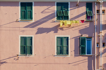Yellow and red clothes are dried under the windows on a rope.
