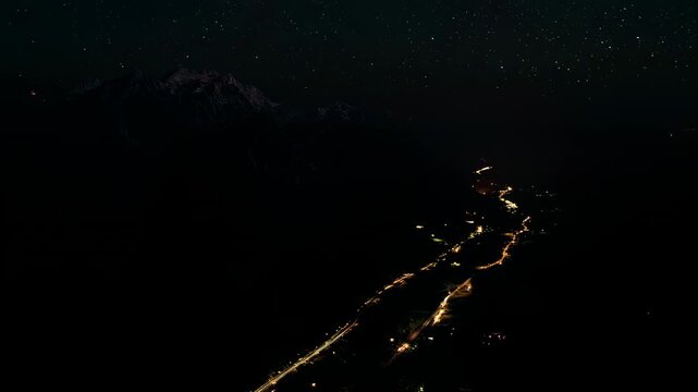 A stunning timelapse sequence of mountain scenery shifting from sunset to night. Night aerial view of illuminated roads