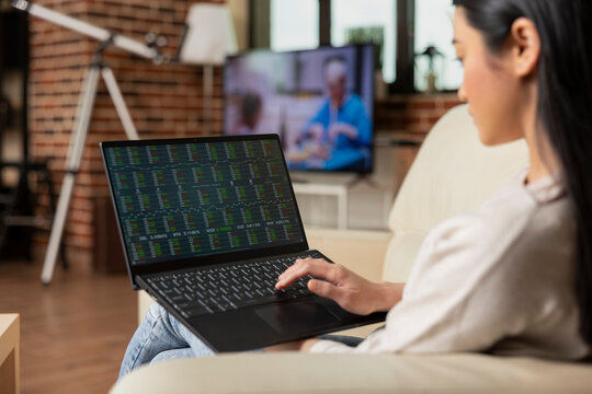 Professional asian manager sitting in home office with laptop, checking financial data and monitoring project performance. Remote female employee concentrating in online business analytics session.