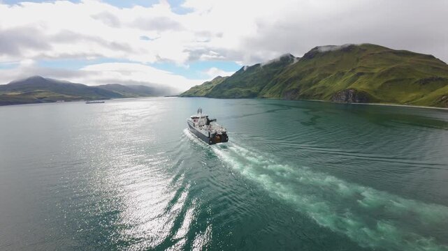Unalaska. Aerial View Large Fishing Vessel Moving Through Calm Alaska Waters Towards the Sun. Commercial trawler sailing in Unalaska Bay, Alaska