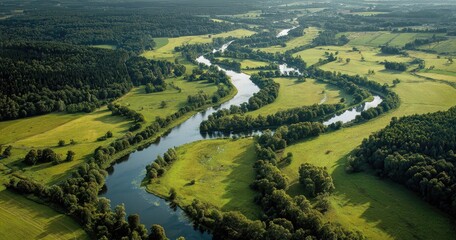 Aerial view of a winding river flowing through lush green fields and forests