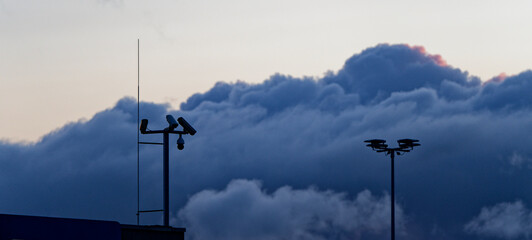 Night sky and star glow above tall camera pole in housing area