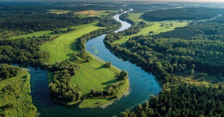 Aerial view of a winding river through vibrant green fields and lush forests