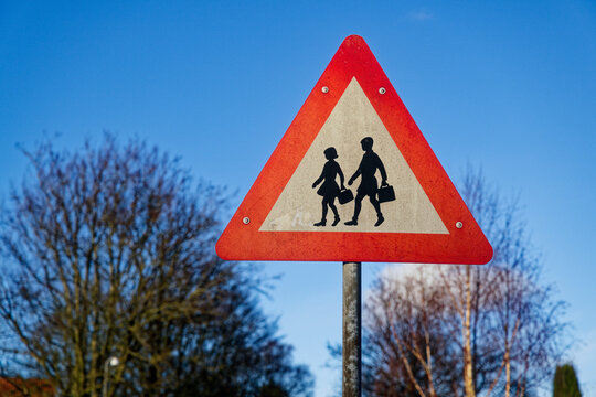 Schoolchildren caution sign with boy and girl crossing figures