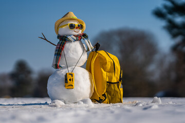Winter Journey. Snowman with suitcase ready for winter vacation. Snowman traveler holding travel...