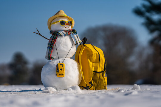 Winter Journey. Snowman with suitcase ready for winter vacation. Snowman traveler holding travel bag. Funny snowman on winter holiday adventure. Winter journey with a festive snow man.