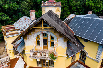 Old abandoned mansion, a majestic yellow building with ornate architecture and dilapidated roofs, surrounded by lush green trees, showcasing a forgotten grandeur. Turliki, Obninsk, Russia © PhotoChur