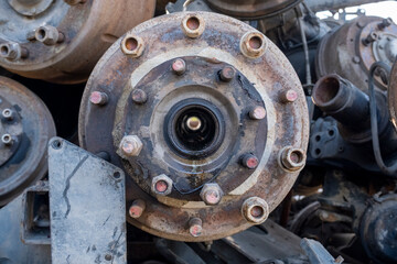 Old rusty truck axles piled in a scrap yard. Discarded heavy truck parts in metal recycling area. Truck axle scrap metal waiting for recycling.