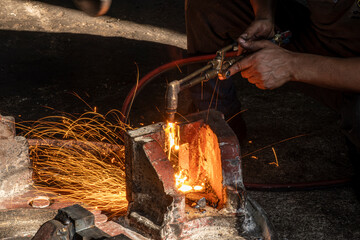 Hands of industrial worker using oxy-fuel torch to cut metal. Worker cutting metal with oxygen torch and flying sparks. Close-up of worker cutting metal with oxygen welding torch.