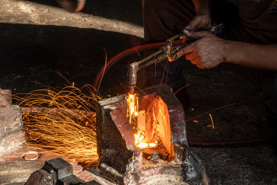 Hands of industrial worker using oxy-fuel torch to cut metal. Worker cutting metal with oxygen torch and flying sparks. Close-up of worker cutting metal with oxygen welding torch.