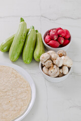 Tortillas with fresh farm vegetables on a white counter, preparing ingredients for a healthy and nutritious meal