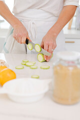 Woman slicing zucchini on kitchen counter for healthy meal preparation, cooking fresh green vegetables