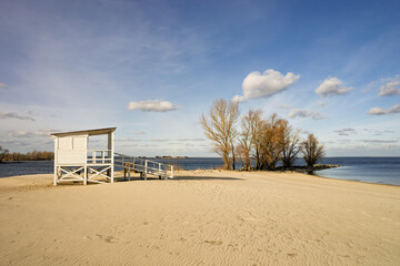 Lifeguard tower standing on a sandy river beach, offering views of the wide Dnieper river under a...