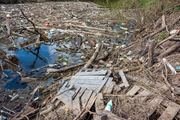 River heavily polluted with plastic bottles, wooden debris, and various trash. Environmental disaster, water obscured by human waste, ecological damage