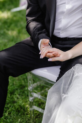 close-up, the groom is sitting and holding the bride's hand