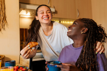Two women sharing laughter and enjoying breakfast together in their cozy kitchen, creating a joyful moment filled with love and connection