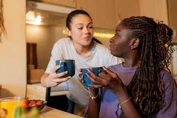 Two women enjoying a cozy morning together, sharing coffee and breakfast in their kitchen, embracing love and connection in their home