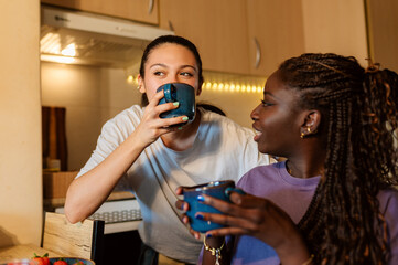 Two women sharing a moment together, drinking coffee and chatting in their kitchen during breakfast