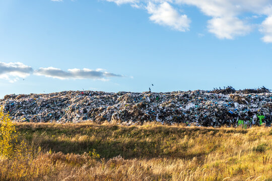 Mountain of waste rises against a clear blue sky in an urban landfill under bright sunlight