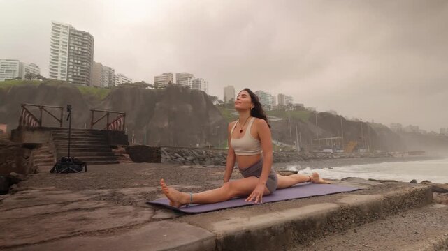 Flexible young woman stretching in a yoga split pose by the ocean