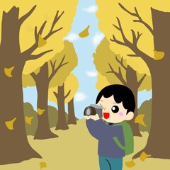 カメラで落ち葉が舞う並木道（イチョウ並木）を撮影する観光客