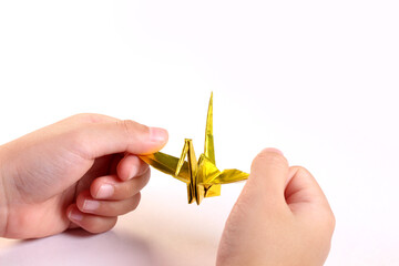 折り鶴を持つ子どもの手
