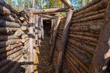 Reconstruction of an ancient log fort in a wooded area during autumn, showcasing natural building materials and historic design