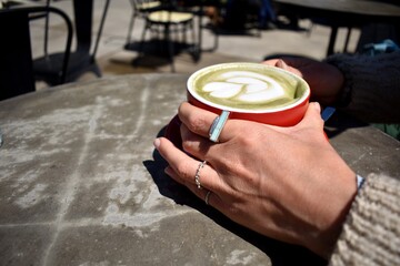 Manos de una mujer joven sosteniendo una taza de café.