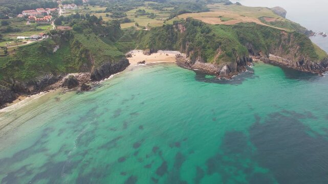 Forward reveal aerial shot of Arama Beach (Playa de Arama) on summer day. Pechon, Cantabria, Spain.