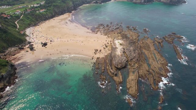 Orbital aerial shot of Amio Beach on summer day. Pechon, Cantabria, Spain.