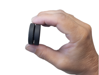 Precise measurement with two black circular magnets held between thumb and forefinger for scientific or industrial applications