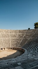 Impressive ancient outdoor stone theater with curved seating tiers reaching toward the sky, showcasing magnificent historical architecture ,preservation, slope, travel