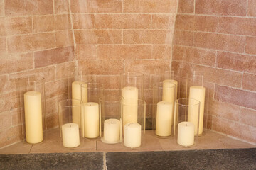 Cluster of pillar candles in fireplace, exposed brick hearth, cozy indoor decor
