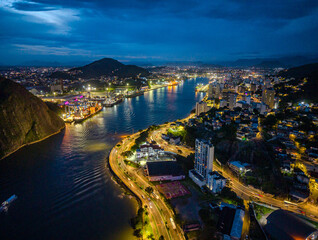 Obraz premium imagem aérea da cidade de Vitória a noite, mostrando o canal de vitória, o porto, as principais vias da cidade e a região comercial.