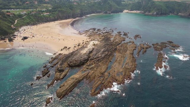 Forward reveal aerial shot of Amio and Arama Beaches on sunny summer day. Pechon, Cantabria, Spain.