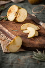 A rustic still life with sliced russet apples sprinkled with cinnamon on a wooden cutting board, evoking a cozy, autumnal mood