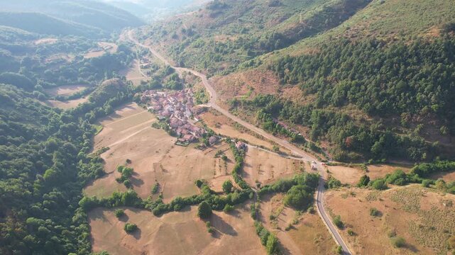 Backward reveal aerial footage of Santa Marina de Valdeon village on sunny summer evening. Picos de Europa, Leon, Spain.
