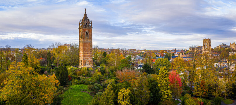Cabot Tower surrounded by colorful autumn trees in Brandon Hill Park, with historic Bristol architecture in the background.