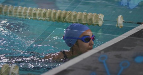 Swimmer gripping pool edge near floating lane rope at lap pool, with blue swim cap, goggles